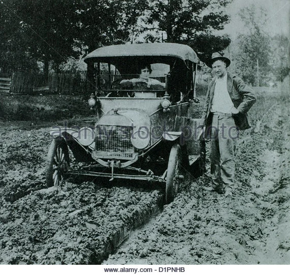 woman-in-ford-model-t-car-on-muddy-road-with-man-standing-next-to-d1pnhb.webp